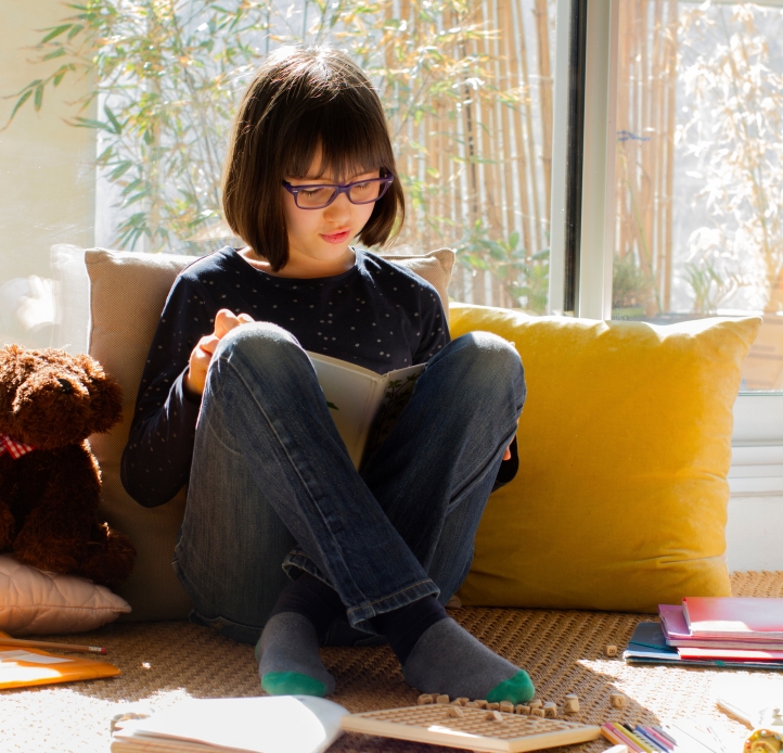 middle school girl reading book by window