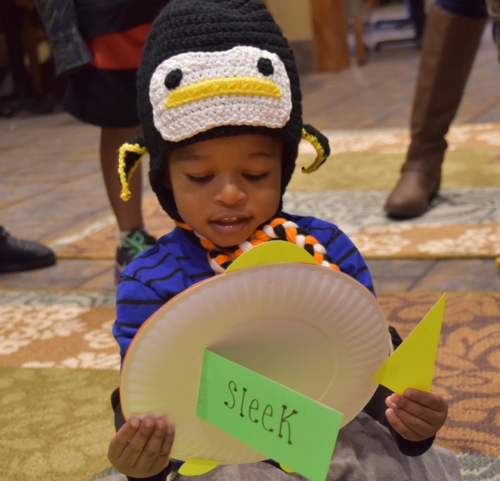Student holding craft in a penguin hat